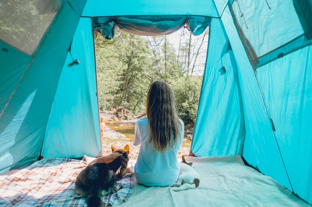 Viaggiatore turistico femminile in un campo in una foresta con i suoi cani insieme in un viaggio nella natura.