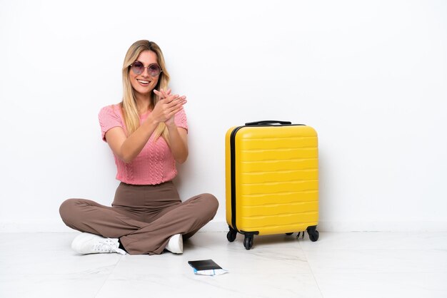 Viaggiatore uruguaiano donna seduta sul pavimento isolato su sfondo bianco che applaude dopo la presentazione in una conferenza