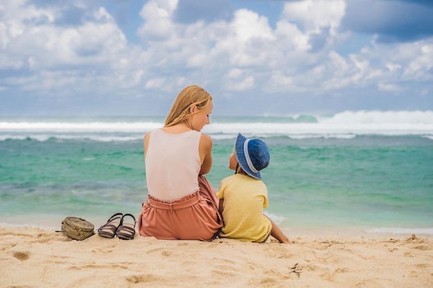 Viaggiatori di mamma e figlio sull'incredibile spiaggia di Melasti con acque turchesi, isola di Bali, Indonesia. Viaggiare con il concetto di bambini