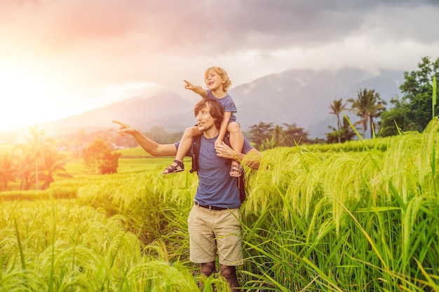 Viaggiatori di papà e figlio sulle bellissime terrazze di riso di Jatiluwih sullo sfondo dei famosi vulcani di Bali, in Indonesia. Viaggiare con il concetto di bambini. con la luce del sole