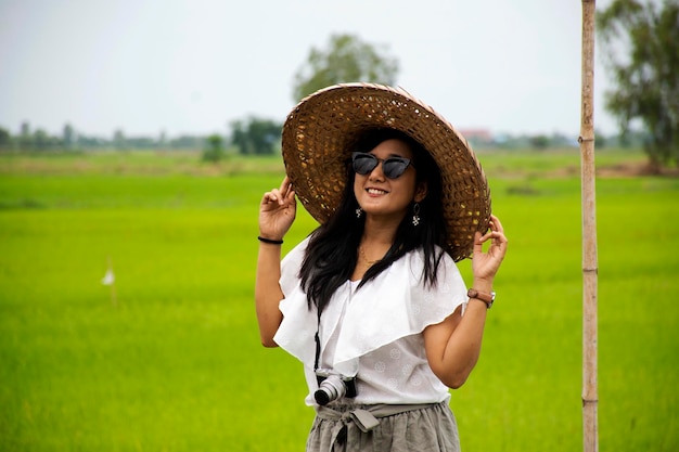 Viaggiatori donna tailandese in posa ritratto per scattare foto con cappello di bambù in stile vietnam all'aperto e giardino campo di riso al bar caffetteria ad Ayutthaya Thailandia