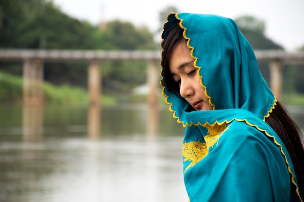 Viaggiatori donne tailandesi da sole che indossano abiti mon stile etnico per scattare foto solitario sul lungofiume di Mae Khlong o fiume Meklong a Ban Pong in serata a Ratchaburi Thailandia