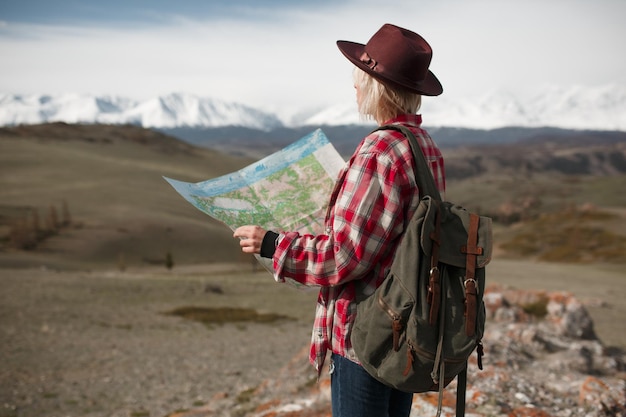 Viaggiatrice con cappello e mappa sullo sfondo delle montagne