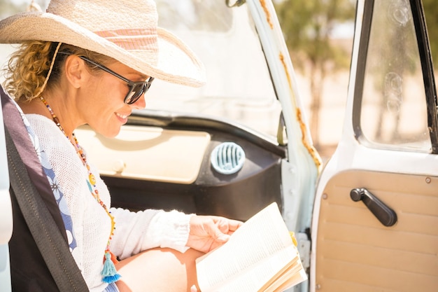 Viaggio allegro felice della donna all'interno di una lettura del furgone. un libro di carta in una soleggiata giornata di vacanza luminosa