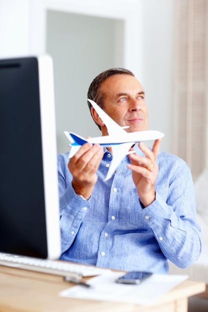 Viaggio di pianificazione Felice uomo maturo azienda aereo giocattolo a casa Viaggio di pianificazione Ritratto di un uomo maturo felice con aereo giocattolo a casa