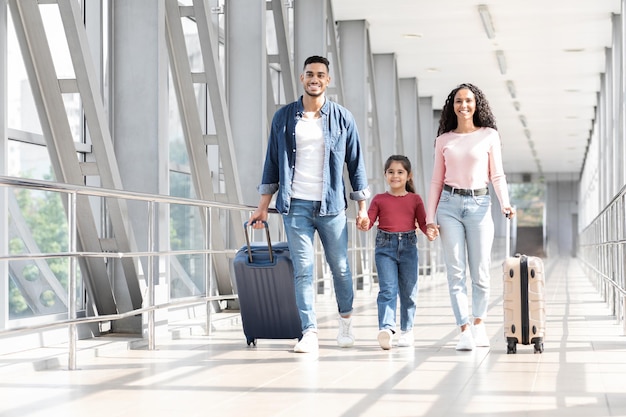 Viaggio di vacanza felice famiglia araba che cammina con i bagagli al terminal dell'aeroporto