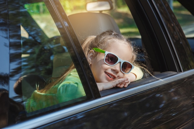 Viaggio in macchina in famiglia giro insieme ragazza che indossa occhiali da sole