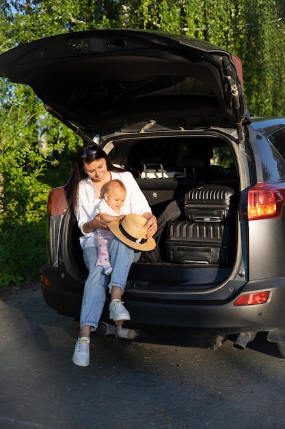 Viaggio in macchina Viaggio con un bambino in macchina Madre e figlia siedono in un'auto con il bagagliaio aperto