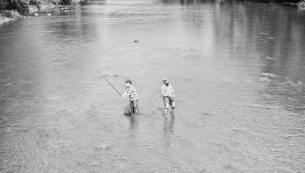 Viaggio Pesca d'altura amicizia maschile padre e figlio avventure di pesca hobby e attività sportiva Esca per trota due pescatori felici con canna da pesca e rete ricreazione e tempo libero all'aperto