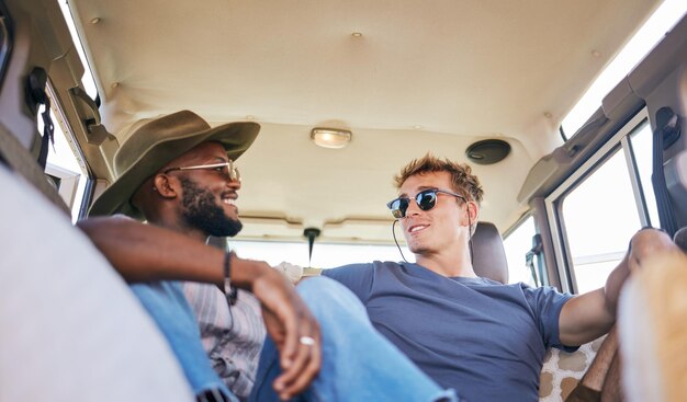 Viaggio su strada e uomini amici in conversazione mentre si è seduti in roulotte durante le vacanze estive Sorriso felice e persone interrazziali che si rilassano parlando e legando durante il viaggio o l'avventura delle vacanze