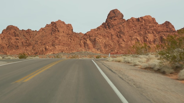 Viaggio su strada, guida auto nella Valley of Fire, Las Vegas, Nevada, USA. Autostop in viaggio in America, viaggio in autostrada. Formazione rocciosa aliena rossa, il deserto del Mojave sembra Marte. Vista dall'auto.