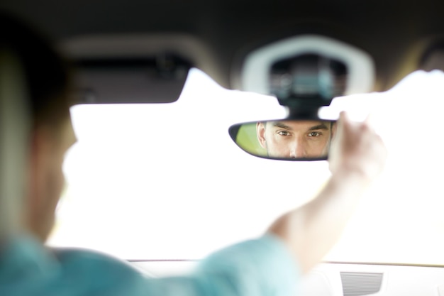 viaggio su strada, trasporto e concetto di persone - uomo alla guida di un'auto che regola lo specchietto retrovisore