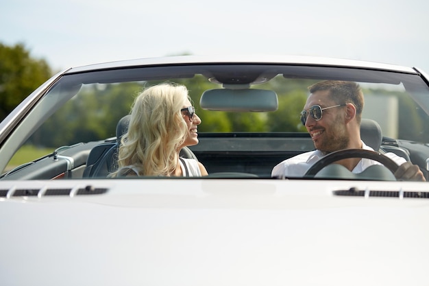 viaggio su strada, viaggio, incontri, coppia e concetto di persone - uomo e donna felici che guidano in auto cabriolet all'aperto