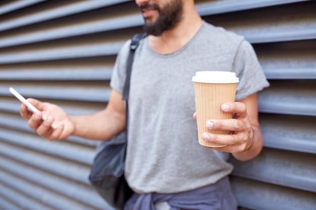 viaggio, turismo, comunicazione, tecnologia e concetto di persone - primo piano dell'uomo con zaino e tazza di caffè che manda messaggi sullo smartphone sulla strada della città