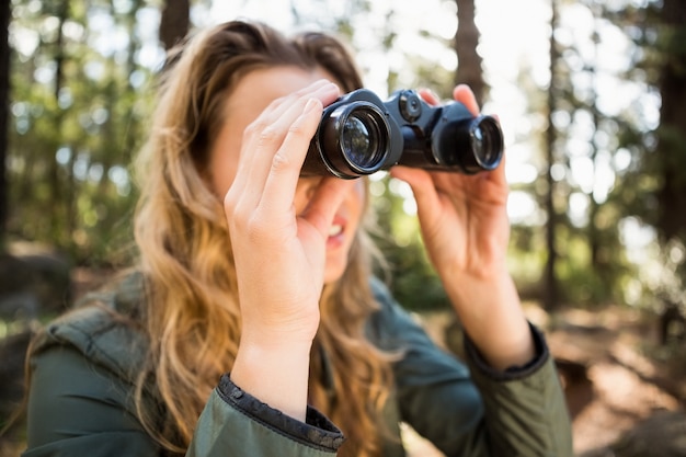 Viandante bionda che osserva tramite il binocolo