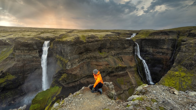 Viandante che esamina le grandi cascate in Islanda al tramonto