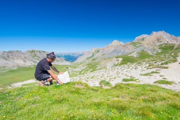 Viandante che legge la mappa di trekking mentre riposa al punto panoramico della montagna