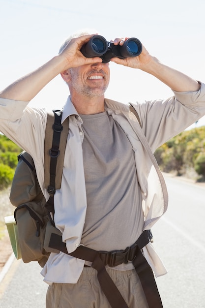 Viandante che si leva in piedi sulla strada che osserva tramite il binocolo