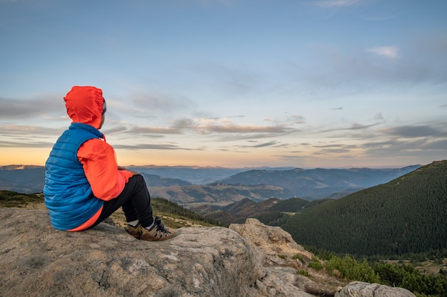 Viandante del ragazzo del bambino piccolo che si siede in montagne che godono della vista del paesaggio stupefacente della montagna.