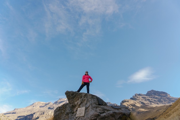 Viandante della donna al bordo della scogliera della cima della montagna