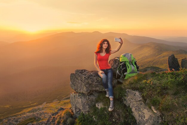 Viandante della donna che prende la foto di auto sul picco di montagna