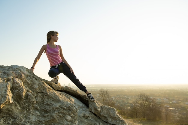 Viandante della donna che scala grande roccia ripida un giorno soleggiato. La giovane scalatrice supera la difficile via di arrampicata. Ricreazione attiva nel concetto di natura.