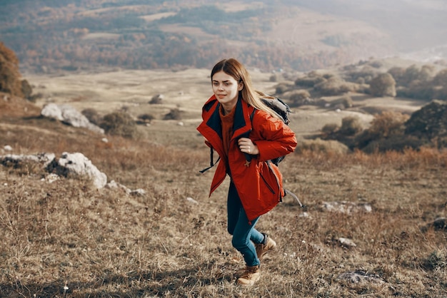 Viandante della giovane donna che viaggia nelle montagne sulla natura e sullo zaino dei jeans della giacca dello zaino del paesaggio
