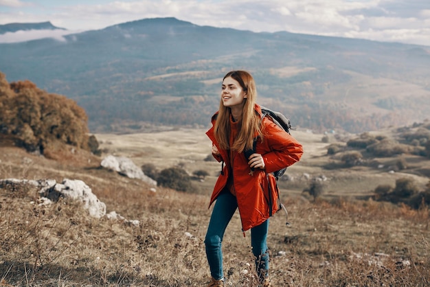 Viandante della giovane donna che viaggia nelle montagne sulla natura e sullo zaino dei jeans della giacca dello zaino del paesaggio