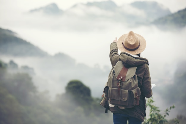 Viandante della giovane donna con lo zaino che guarda la mappa di trekking, facente un escursione concetto.