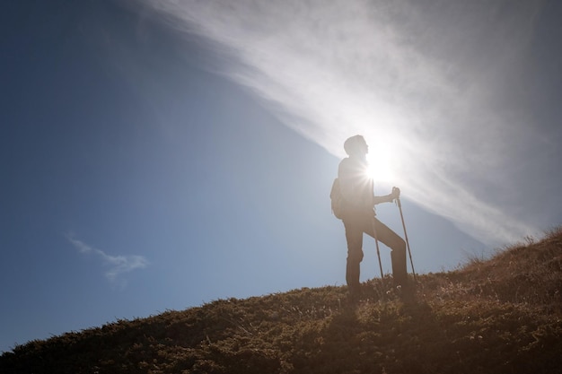 Viandante della giovane donna con uno zaino sulla cima della montagna