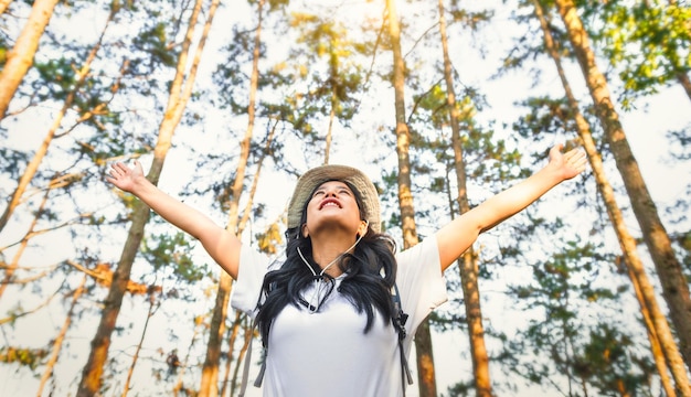 Viandante di viaggio che cammina nella foresta naturale felice con il braccio alzato