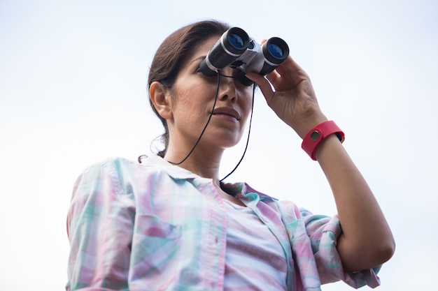 Viandante femminile che osserva tramite il binocolo