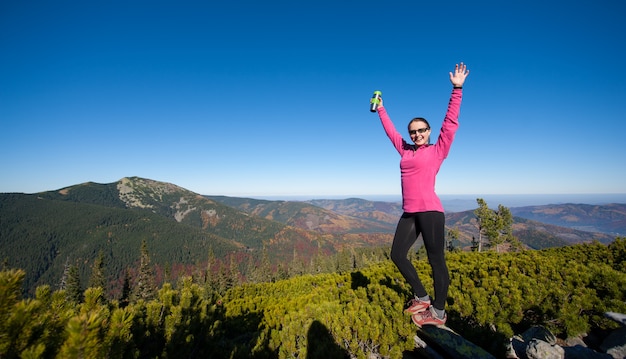 Viandante femminile che raggiunge il suo obiettivo alla cima della montagna