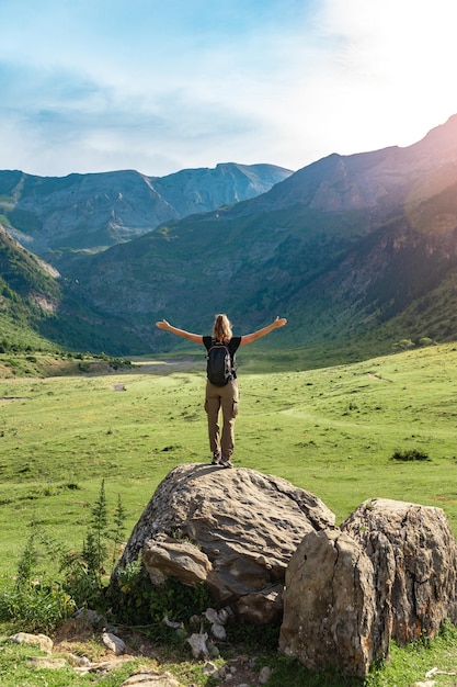 Viandante femminile in cima a una roccia con le braccia alzate godendo di un paesaggio straordinario in estate