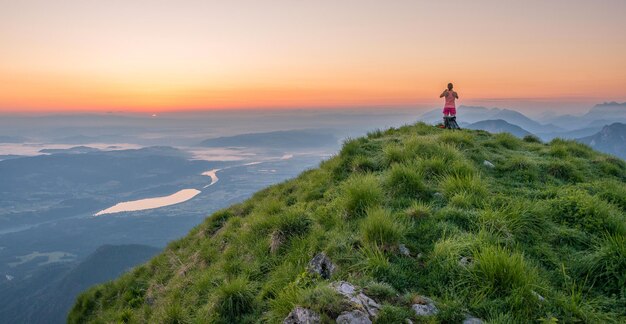 Viandante femminile in cima alla collina all'alba