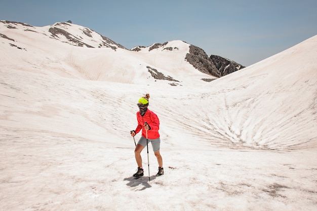 Viandante femminile in una giacca rossa in montagna