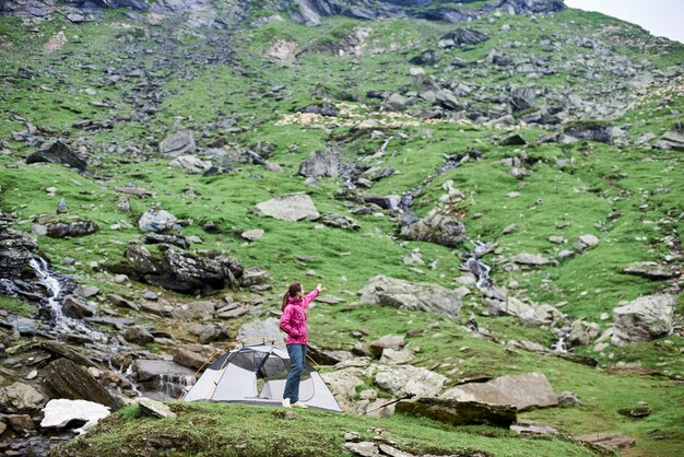 Viandante femminile vicino alla sua tenda nella valle della montagna