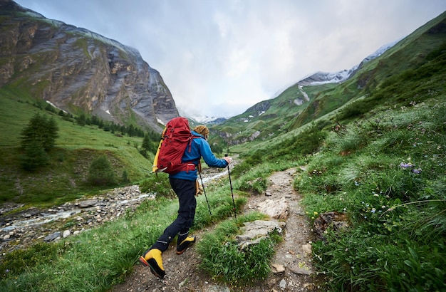 Viandante maschio che cammina giù per il sentiero di montagna rocciosa