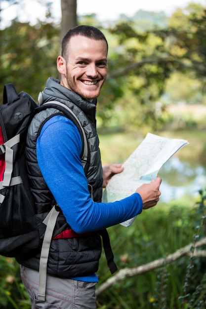 Viandante maschio che tiene una mappa in foresta