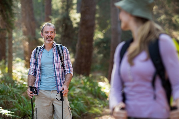 Viandante sorridente che fa un'escursione con i bastoncini da trekking