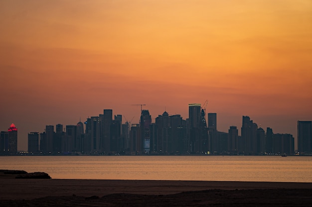 Vibrante Skyline di Doha al drammatico tramonto visto dal lato opposto della baia della capitale.