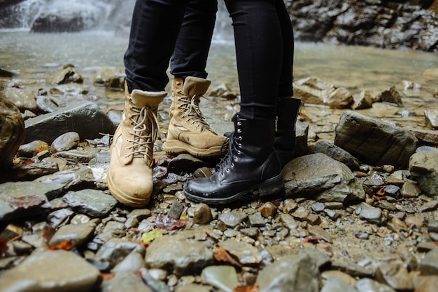 Vicino all'acqua. Persone attive che indossano scarpe comode e si rilassano sulla pietra vicino al fiume di montagna durante il viaggio