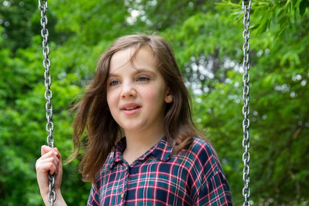 Vicino alle bambine felici che giocano e sedute sull'altalena nel parco naturale