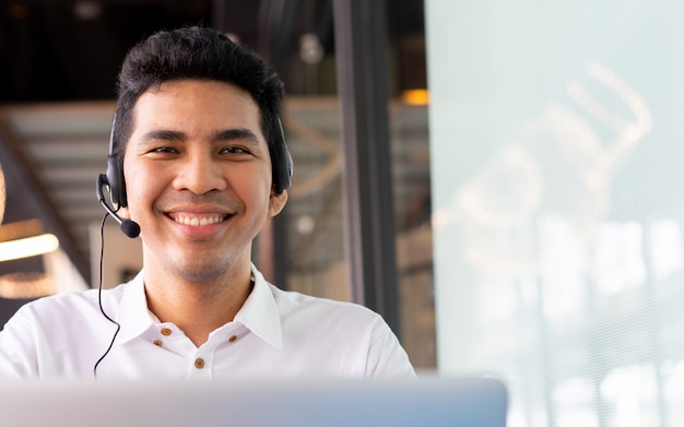 vicino asiatico call center dipendente uomo che lavora sorridente con service-mind