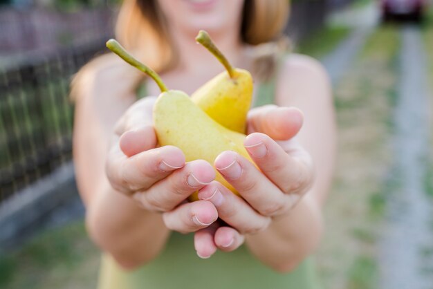 Vicino di mani - donna in possesso di una pera gialla - ringraziamento - giardinaggio