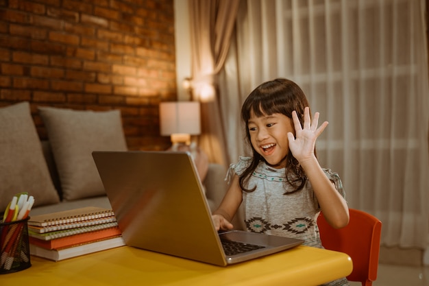 Videochiamata del bambino facendo uso del computer portatile a casa la sera