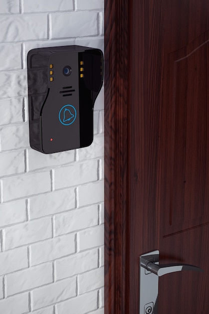 Videocitofono moderno vicino alla porta su uno sfondo di muro di mattoni