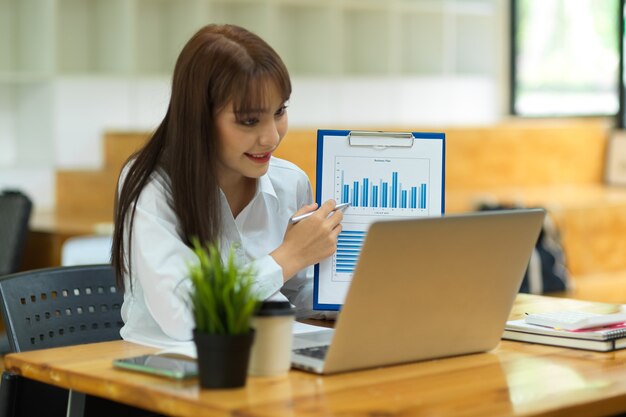 videoconferenza della donna d'affari con il team e visualizzazione del grafico a barre finanziario sulla fotocamera