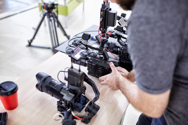 Videografo che gira un film o un programma televisivo in uno studio con una telecamera professionale nel backstage