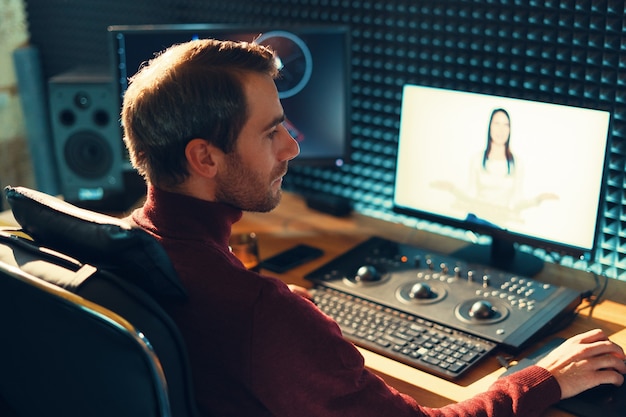 Videografo maschio modifica e taglia filmati e suoni sul suo personal computer